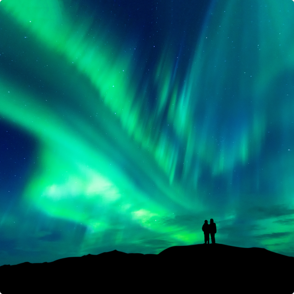 Aurora boreal verde e azul no céu nocturno, observada por duas pessoas em silhueta.